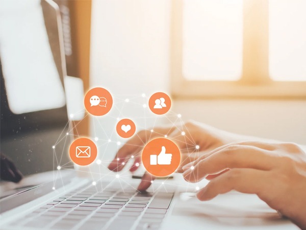 Hands typing on a laptop with floating social media and communication icons.