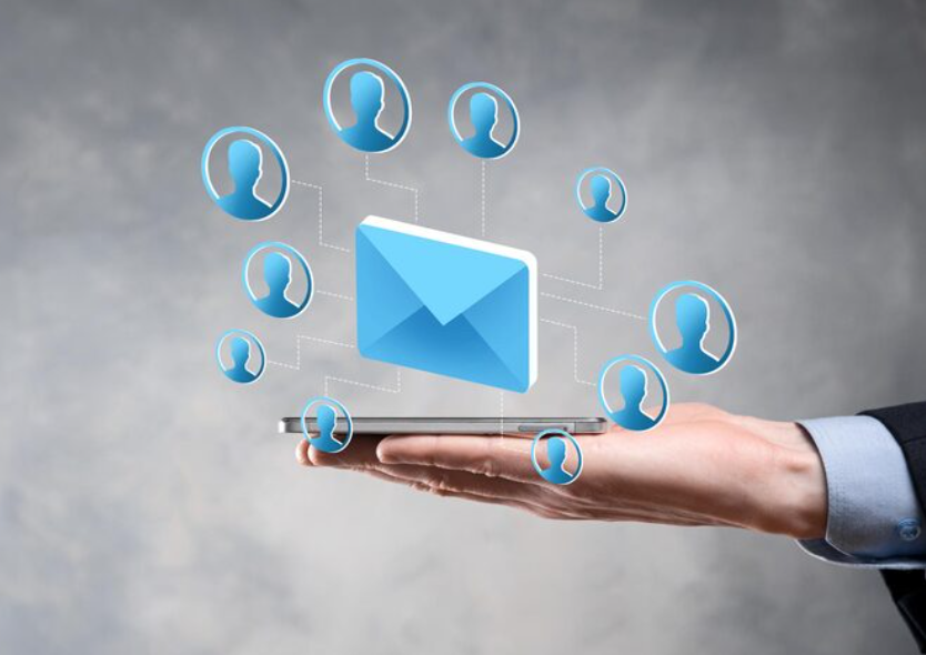 Hand holding a smartphone with a floating email icon connected to multiple user profiles, representing SMS marketing.