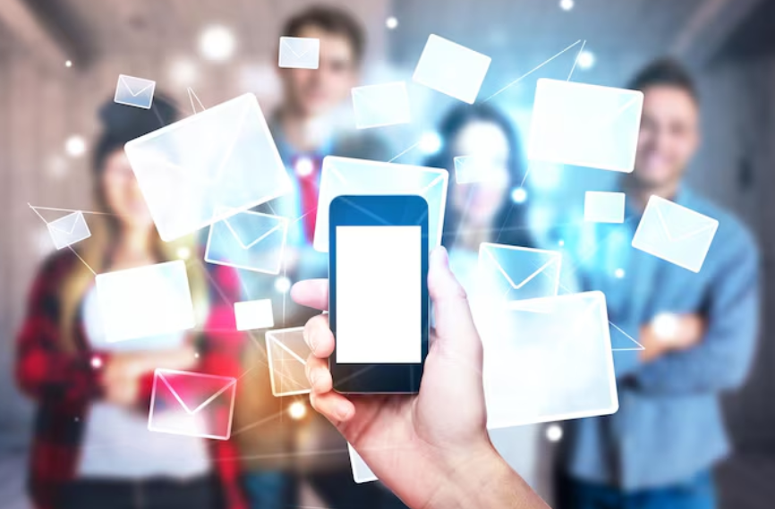 Hand holding a smartphone with floating email icons, representing SMS communication.