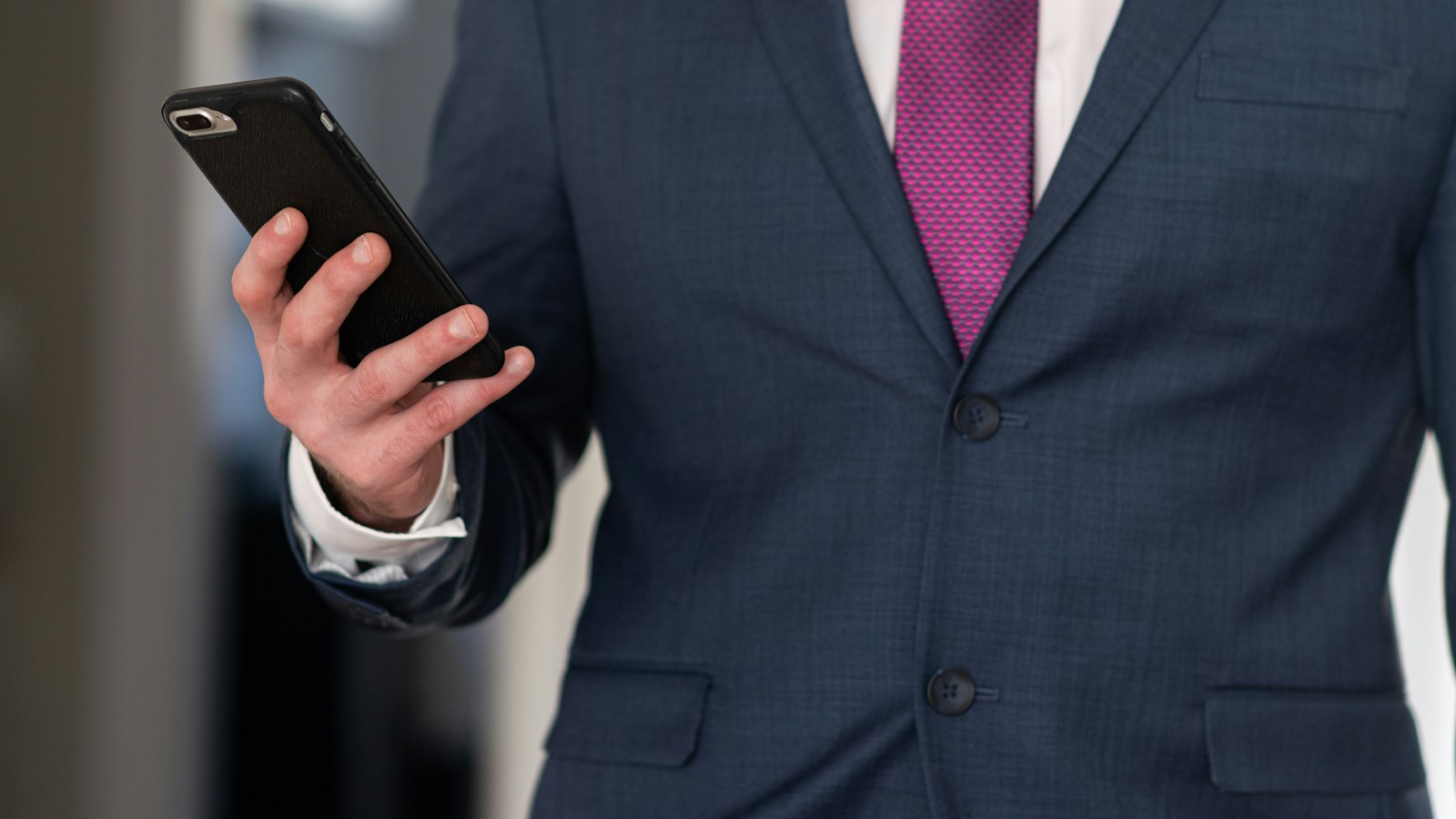 Professional holding a smartphone for comparing sender IDs and short codes