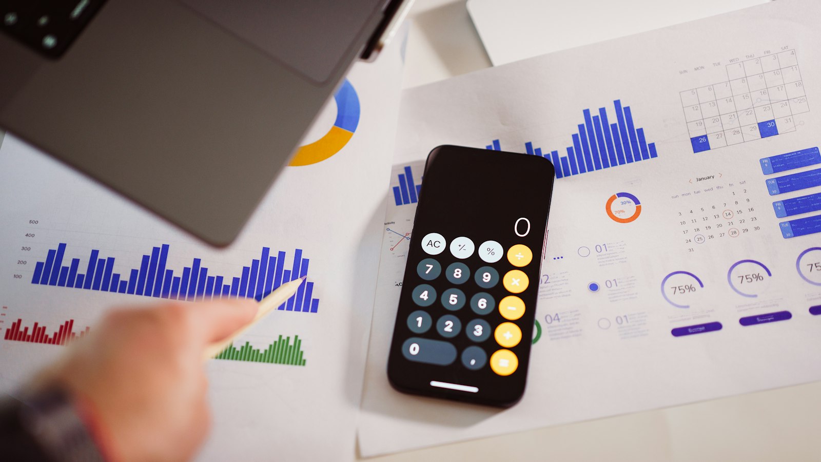 A person using a phone calculator over printed cost charts