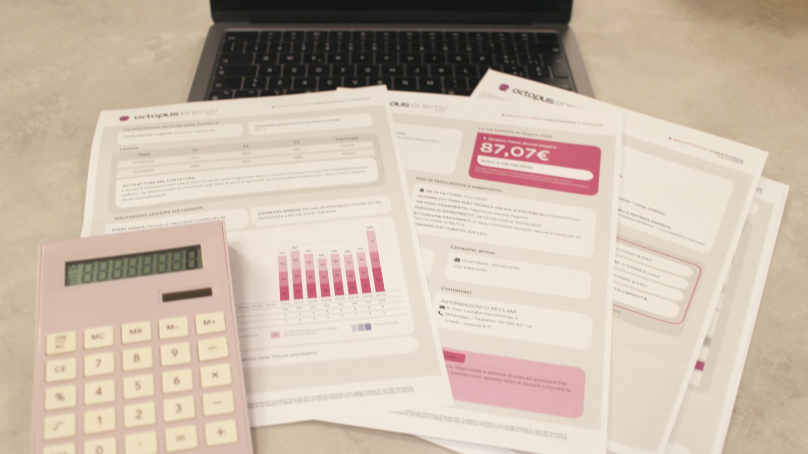 A calculator beside a stack of printed bills and a keyboard